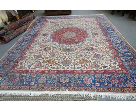 A Tabriz carpet, Persian, the ivory field with a bold faceted madder medallion, all with floral sprays, birds and animals, am