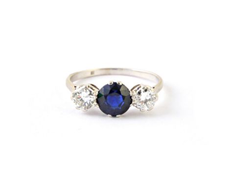 A platinum, diamond and sapphire set three stone ring, claw set with the circular cut sapphire at the centre, between two cir