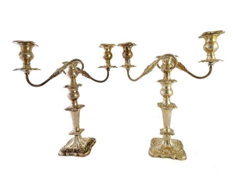 A pair of silver three light table candelabra, each with scrolling fluted arms and on a shaped square base, with foliate and 