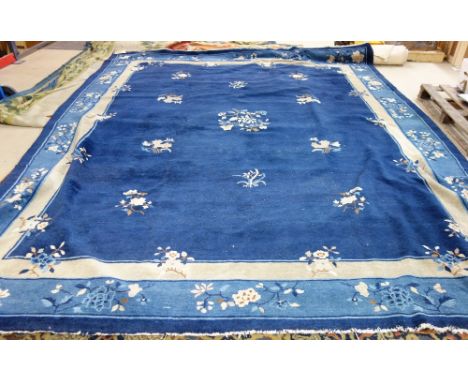 A Chinese carpet, the dark indigo field with delicate floral sprays, a pale indigo floral spray border, 384cm x 314cm. 