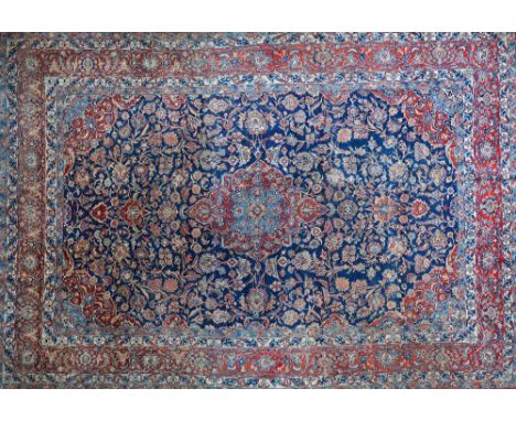 A Kashan carpet, early 20th century, with blue field and central red and blue medallion, multiple borders, 368cm x 262cm.  Il