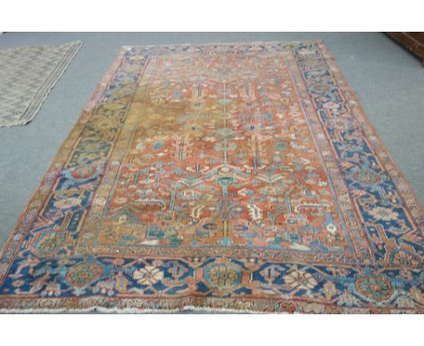 An Heriz carpet, Persian, the madder field with an allover floral spray design, an indigo palmette and flower border, 280cm x