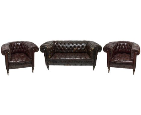 An early 20th century button back rouge leather upholstered Chesterfield three piece suite, to comprise a sofa and a pair of 