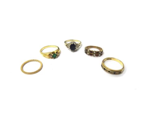 A gold, emerald and diamond set three stone ring, claw set with the step cut emerald at the centre, between two circular cut 