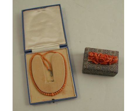 A carved coral floral panel brooch, 5cm long, together with a graduated row of small coral beads, 31.5cm long