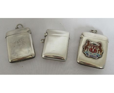 Three hallmarked silver vesta cases, one plain, one with an applied enamel crest for Aberdeen and the other with engraved cre