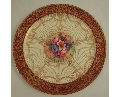 A Royal Worcester plate, decorated with a central panel of flowers by Barker, to a radiated ivory border, to a deep gilded bu