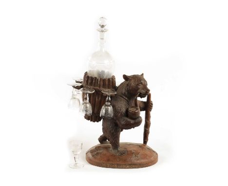 A LATE 19TH CENTURY SWISS CARVED BLACK FOREST BEAR DECANTER STAND modelled as a bear carrying a basket, fitted with a glass d