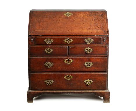 AN EARLY 18TH CENTURY OAK BUREAU the angled hinged fall front revealing a fitted interior of small drawers and pigeon holes a