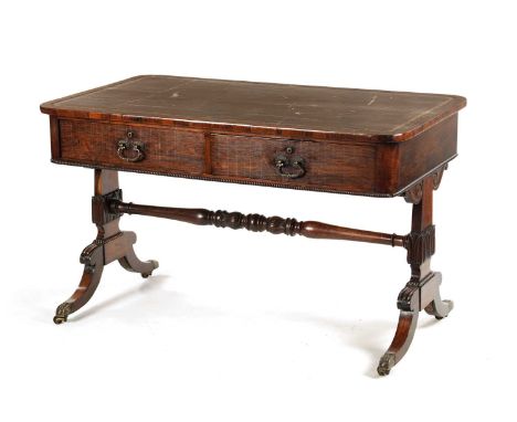 A LATE REGENCY ROSEWOOD LIBRARY TABLE with gilt tooled leather top above a fitted two drawer frieze and gilt brass rococo sty