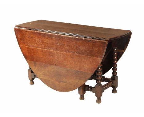 A 17TH CENTURY JOINED OAK GATE LEG TABLE with drop-down hinged sides; raised on a bobbin-turned base with side gates joined b