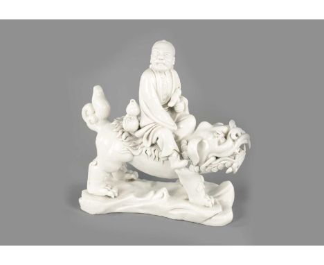 A CHINESE BLANC-DE-CHINE PORCELAIN FIGURE Modelled as Li Tieguai holding his crutch with double gourd riding a foo dog, stand