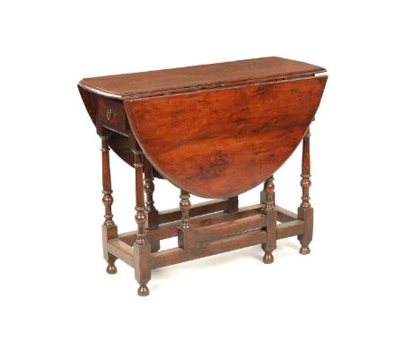 A RARE 17TH CENTURY YEW-WOOD AND ELM GATE-LEG TABLE with hinged moulded edge oval top, double end drawers and raised on a rin