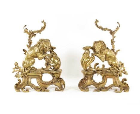 A PAIR OF REGENCY ORMOLU CHENETS OF ROCOCO DESIGN with scrolled open leafwork bases set with lions and branchwork fire tool h