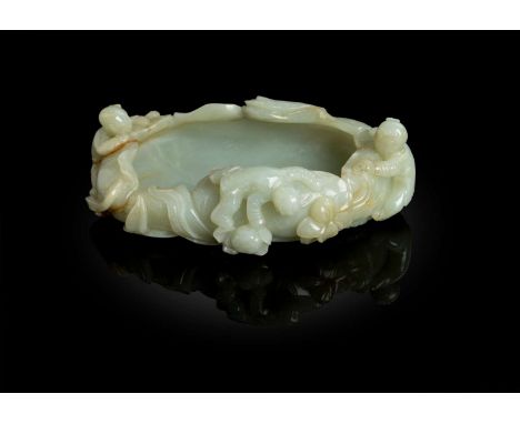  CELADON JADE WITH RUSSET SKIN 'BOYS AT PLAY' BRUSH WASHER QING DYNASTY, 19TH CENTURY 清 青玉帶皮雕嬰戲蓮池筆洗in the form of a large lot