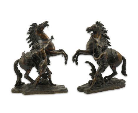 After Guillaume Coustou (1677-1746), a pair of bronze Marli horse groups, each with a groom holding a rearing stallion, signe