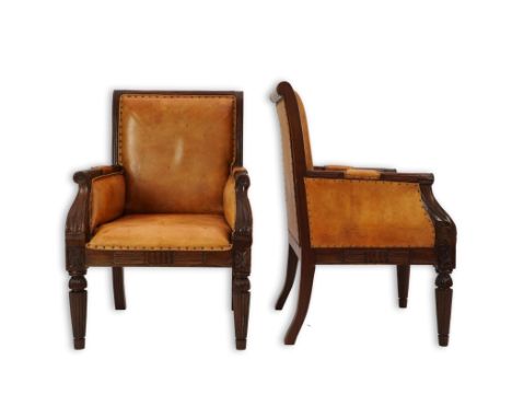 A pair of early 19th century Anglo Indian carved mahogany armchairs with tan leather upholstered backs, seats and arm pads, t
