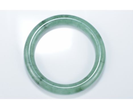 A Chinese pale and green jadeite bangle. 6cm inner diameter