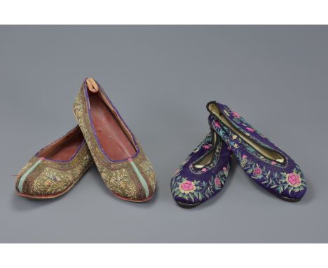 A pair of Chinese early 20th century purple ground embroidered women's shoes with floral decoration together with a pair of V