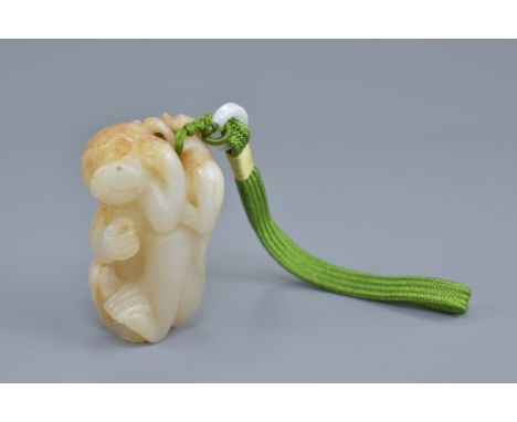 A Chinese pale celadon and brown jade pendant carved as a monkey with baby. 7cm height