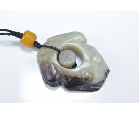 A Chinese celadon and brown jade frog with separate central jade piece with 'Shou' character wishing long life. 5.5cm length