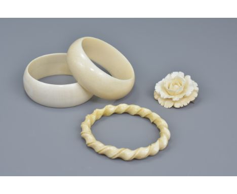 Pair of ivory bangles, together with another ivory bangle with rope twist design, and a carved ivory brooch. (4)