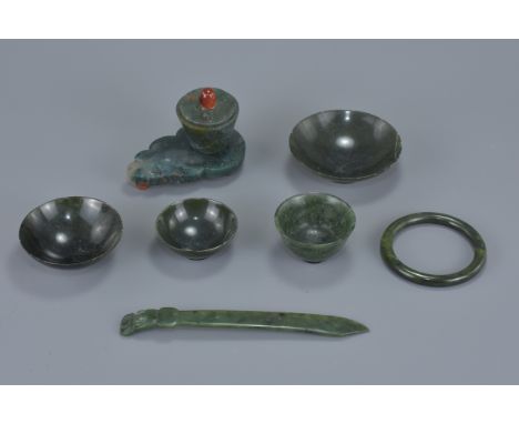 A group of seven Chinese jade items including a pot and cover on stand, a bangle, three dishes, a cup and a hair pin. hair pi
