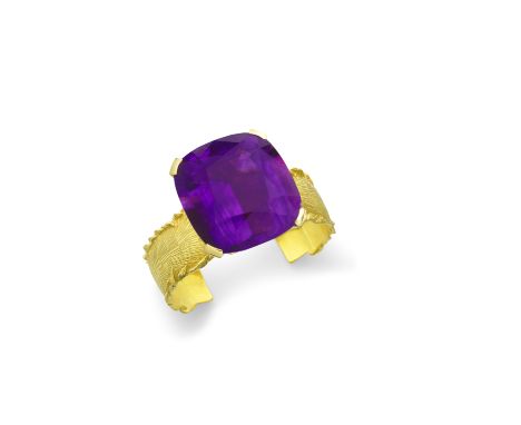 SIMON BENNEY: AMETHYST BANGLE, 2000The cushion shaped amethyst, mounted high on a textured 18 carat gold cuff with feathered 