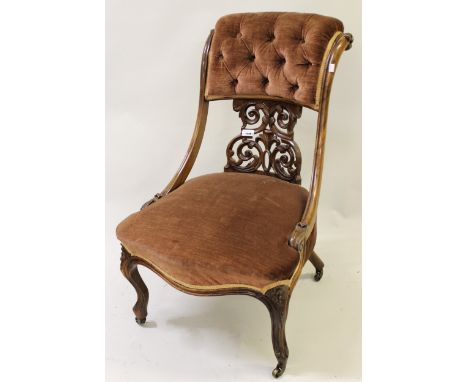 Victorian rosewood and pink button upholstered low seat nursing chair with a pierced, carved centre back, on cabriole support