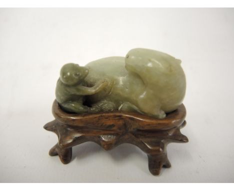 Late 19th / early 20th Century Chinese moss green jade miniature figure of a reclining horse and monkey, on a hardwood stand,