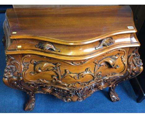 A reproduction serpentine three drawer carved commode chest, 97cm wide