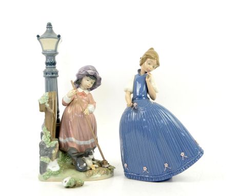 Two Lladro figures, girl standing by a lamp (foliage damaged), and girl in a blue dress holding a flower (one finger broken),