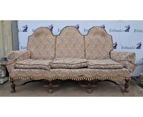 † 1920s three-seater sofa, the arched back over scrolling arms on turned and block legs with scroll feet and shaped cross str