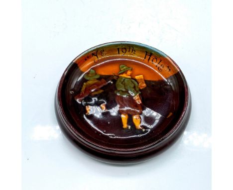 Round shallow dish pipe rest coaster depicting two men playing golf. Marked Ye 19th Hole. Royal Doulton backstamp on bottom. 