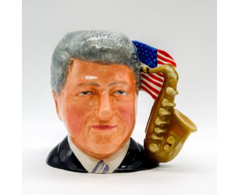 Prototype ceramic molded figure of the 42nd president in a navy suit jacket; saxophone and American flag handle.Royal Doulton