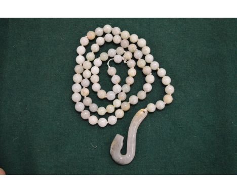 A jade bead necklace with curving serpent pendant.