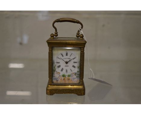 A small brass carriage clock with porcelain dial and panels.