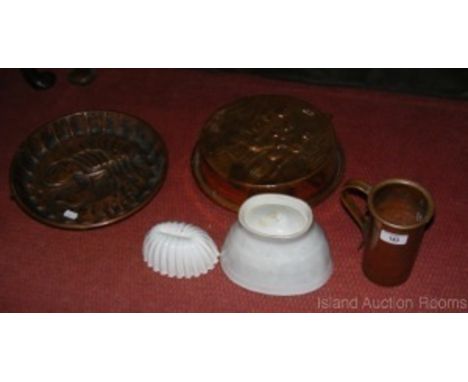 Two ceramic and two copper jelly moulds and a ditto measure