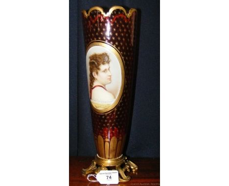 A 33cm high cranberry glass vase on brass base with ceramic oval portrait mount