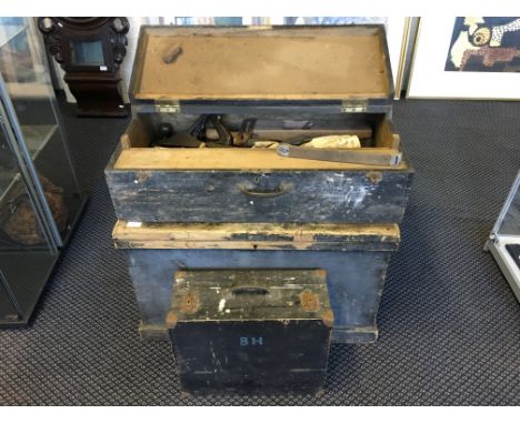 Three wooden tool boxes in graduating sizes, with various tools.