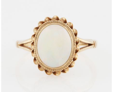 A 9ct yellow gold opal ring, set with a central oval opal cabochon, measuring approx. 10x8mm, with rope twist border, hallmar