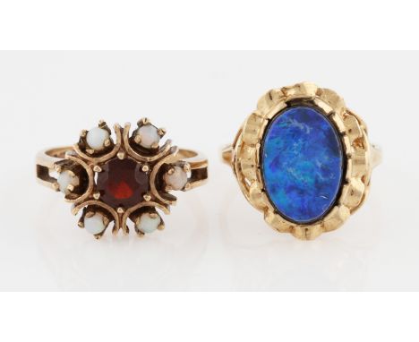 Two hallmarked 9ct yellow gold rings, one set with a central red paste surrounded by opal cabochons, the other set with an op