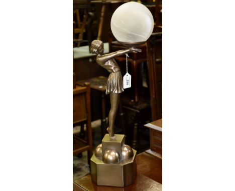 A contemporary table lamp in the form of an Art Deco girl in a gymslip holding a ball on a plinth.