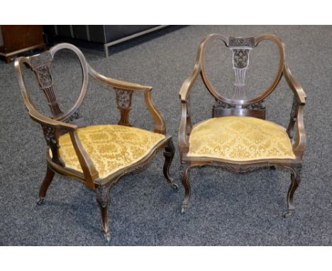 A pair of late Victorian drawing room chairs, heart shaped backs pierced and carved with scrolling foliage, serpentine fronte