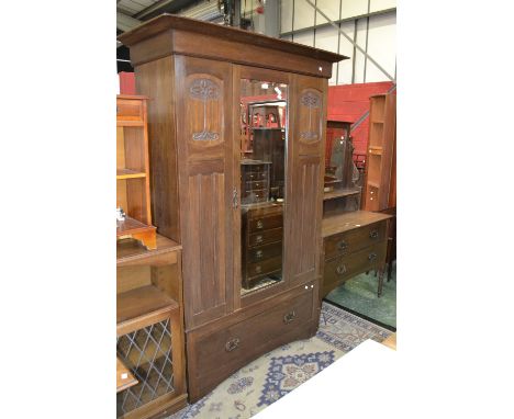 An Art Nouveau oak bedroom suite comprising a double wardrobe, outswept cornice, central mirrored door flanked by carved pane