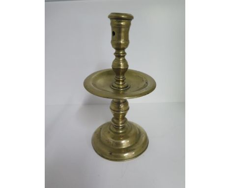 A heavy 18th century brass candlestick, 21cm tall, some bending consistent with age 