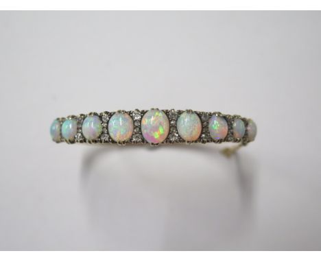 A opal and diamond yellow gold bangle, 5.5 cm x 6.5 cm external, largest opal approx 9mm x 7mm, in good condition apart from 