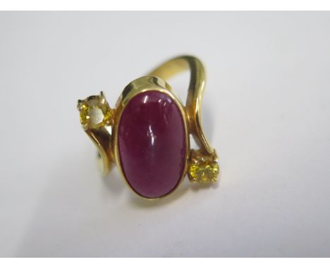 A 9ct 375 yellow gold ring set with an oval corundun glass composite 6ct stone flanked by 2 yellow cubic Zirconia stones, siz
