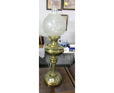 A brass oil lamp with etched glass shade