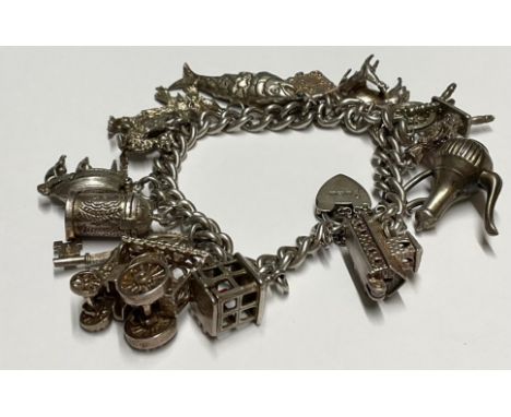 A silver charm bracelet with fourteen charms inc traction engine, dragon, stein,  spinning wheel etc, 67.9g gross